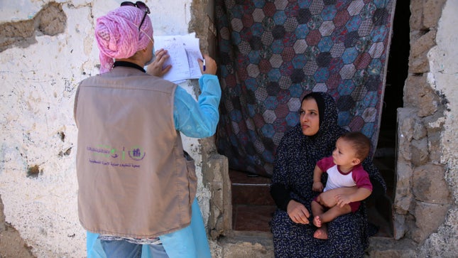 Ein Mitarbeiter der Palästinensischen Vereinigung für Familienplanung und -schutz hilft 2021 einer Frau und ihrem Kind. 